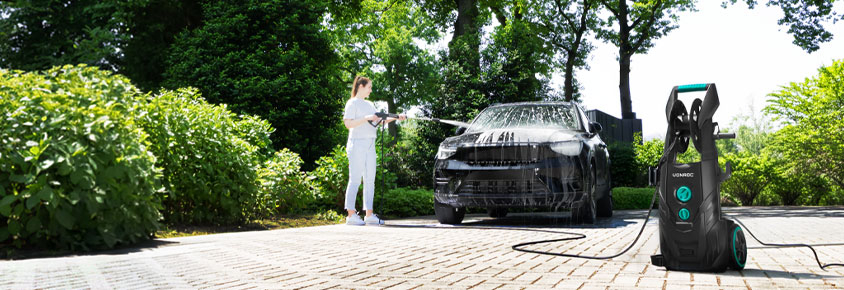 Mulher limpa carro com a máquina de limpeza de alta pressão VONROC V25